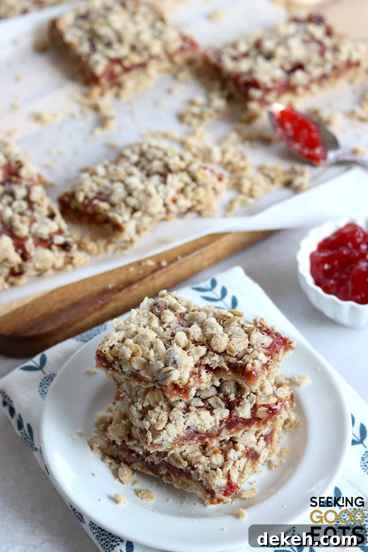 Strawberry oatmeal bars cut into squares, and three stacked on a small white plate.
