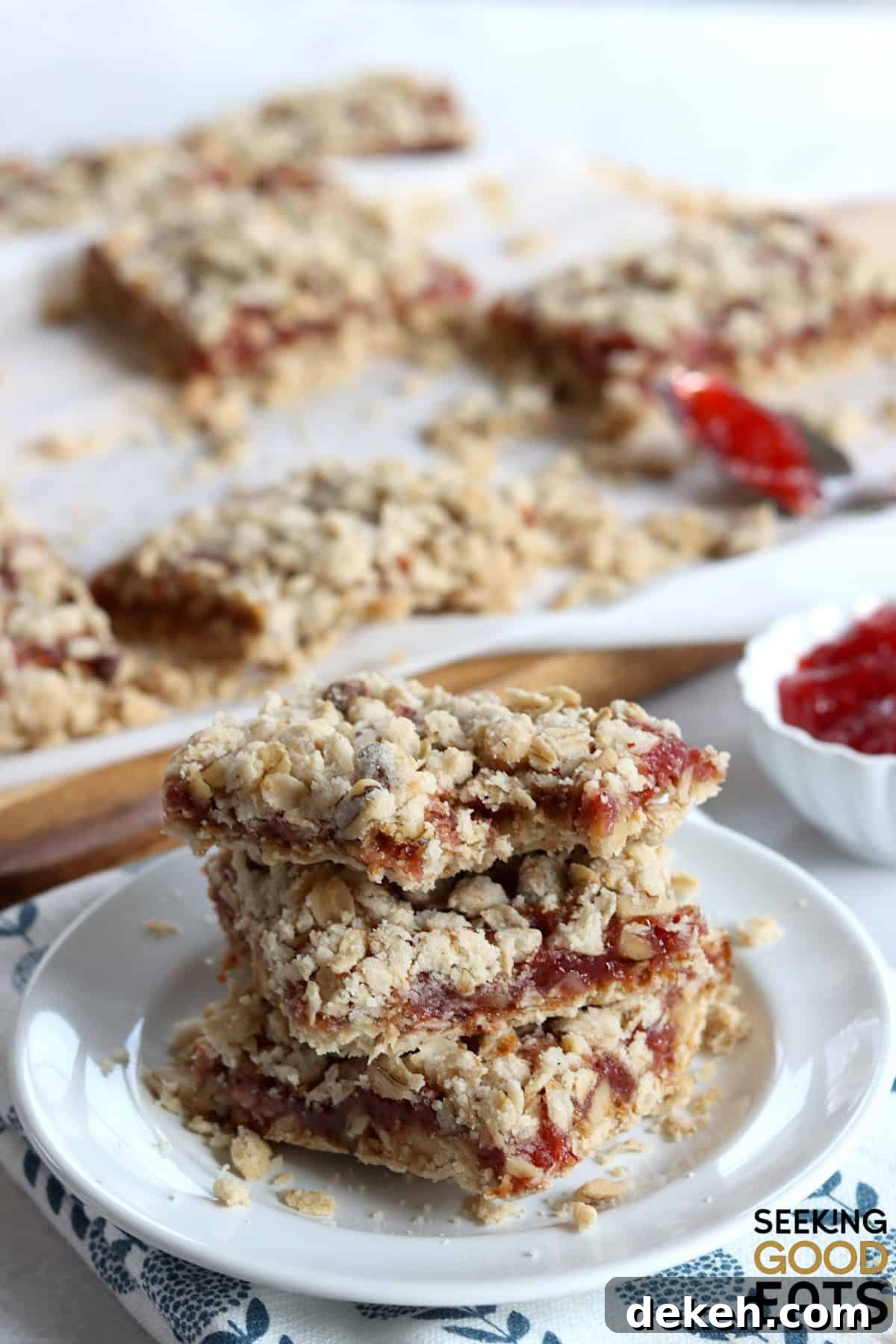 Strawberry oatmeal bars cut into squares, and three stacked on a small white plate.