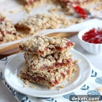 Three strawberry oatmeal bars stacked on a small white plate.