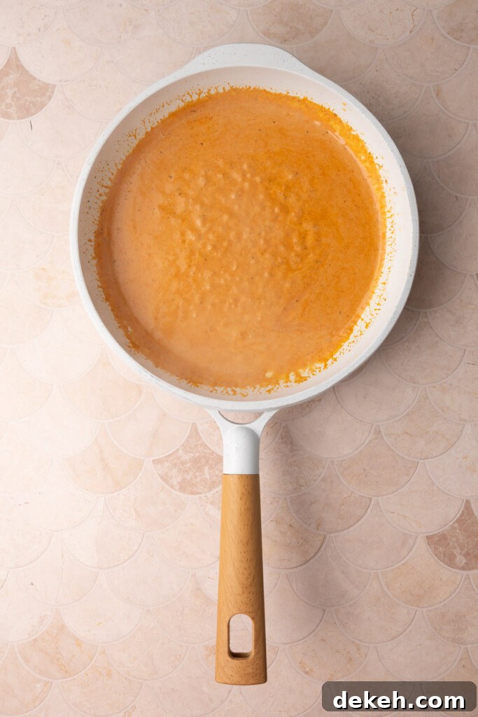 Butter, garlic., tomato, paste, cream, and Cajun seasoning all thickening in a pan. 