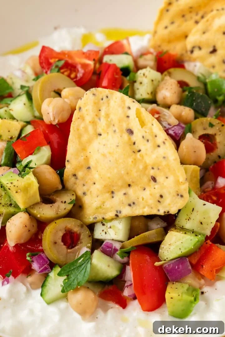 Cottage cheese greek salad in a bowl with a tortilla chip, ready to scoop.
