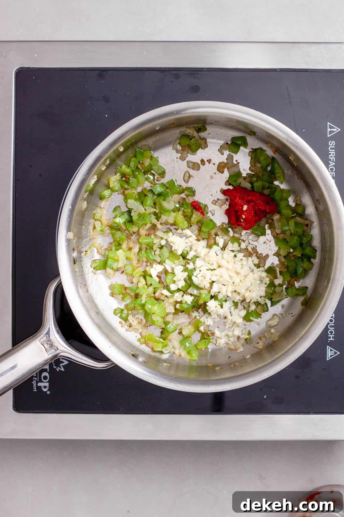 Onions, garlic, peppers and tomato paste in a medium saucepan cooking.