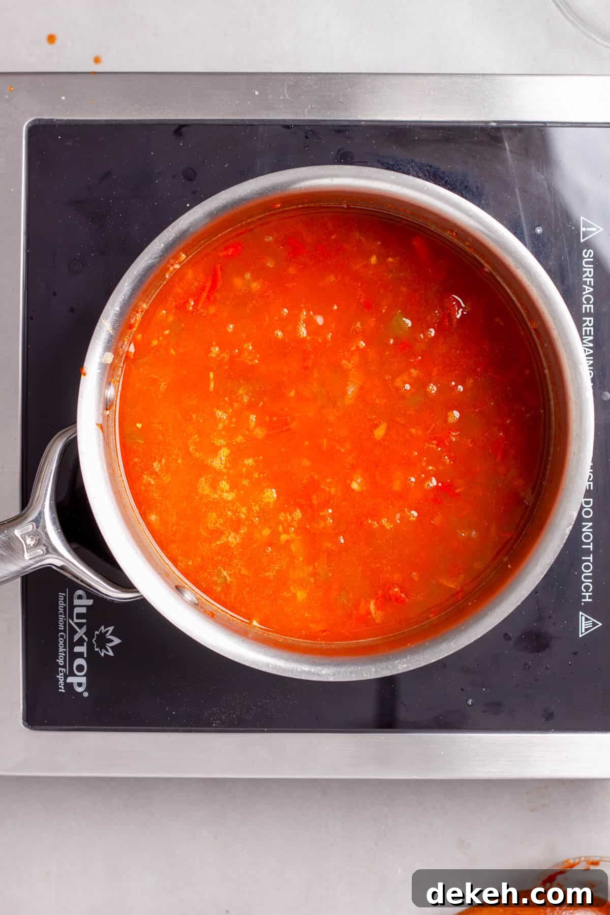 Vegetable broth added to a saucepan with bulgur and aromatics for bulgur pilaf.