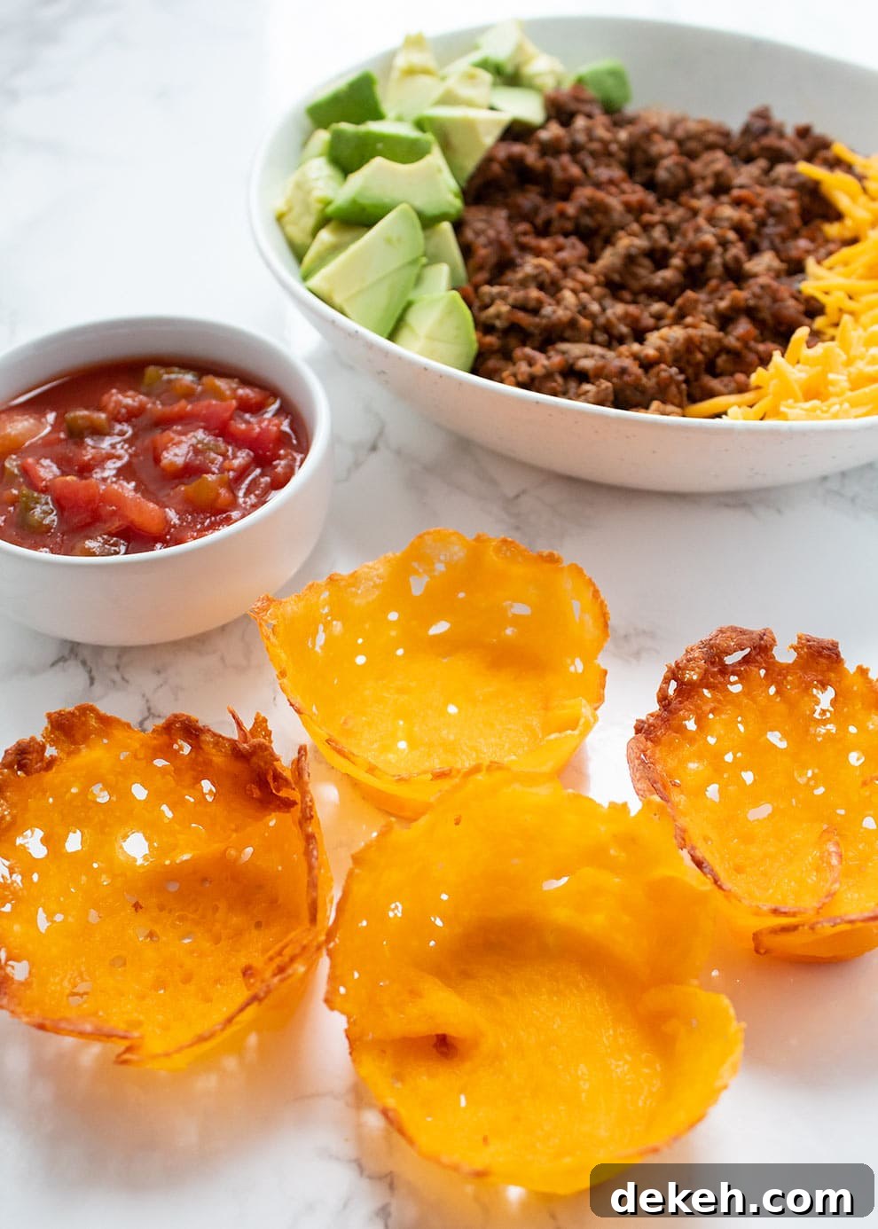 keto taco cups with various meats and cheeses in the background