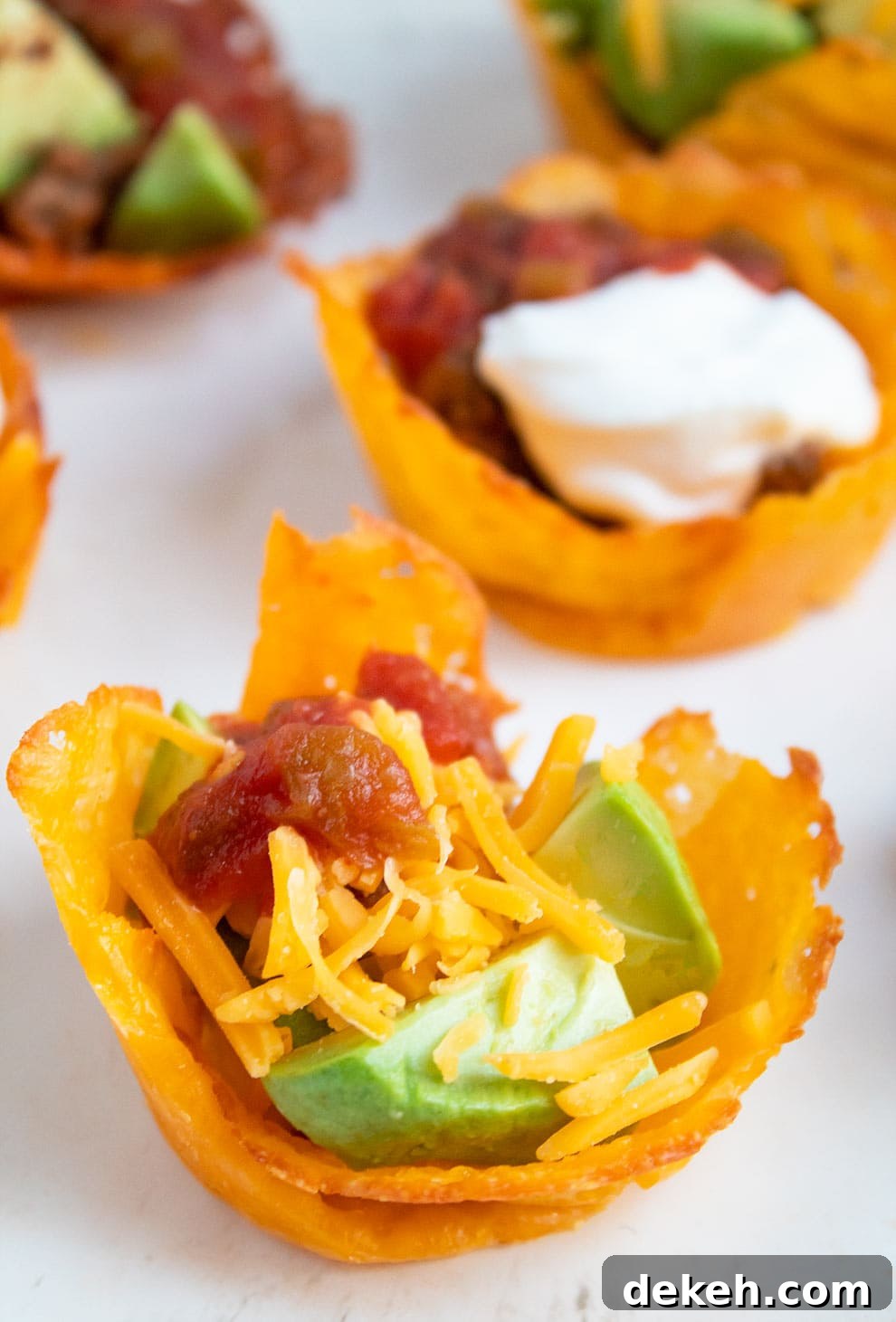 keto taco cups containing fillings sitting on a light grey plate