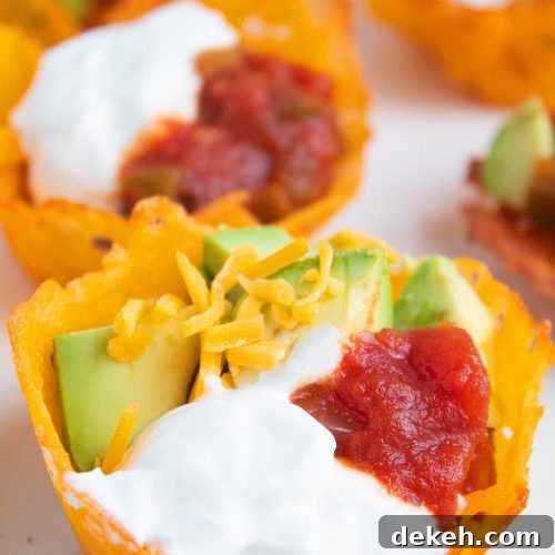 keto taco cups closeup with sour cream, avocado, cheese, and salsa