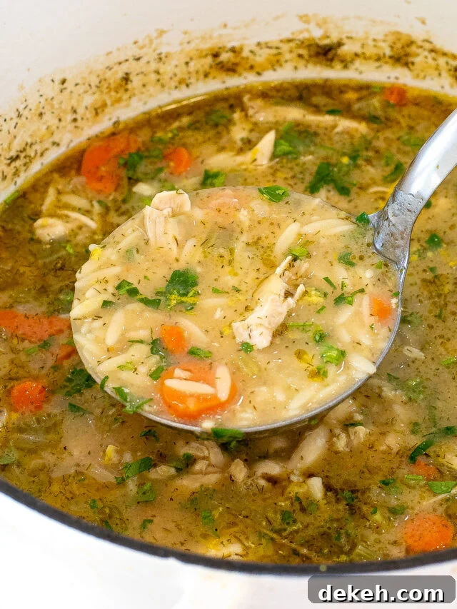 Lemon orzo soup with a ladle scooping out a portion of soup from the pot. 