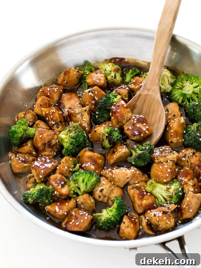 Honey garlic chicken stir fry in a skillet with a wooden spoon. 