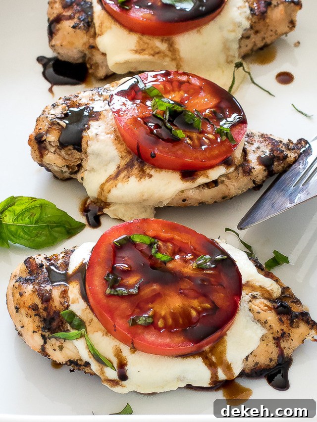 Three pieces of grilled chicken caprese on a white platter. 