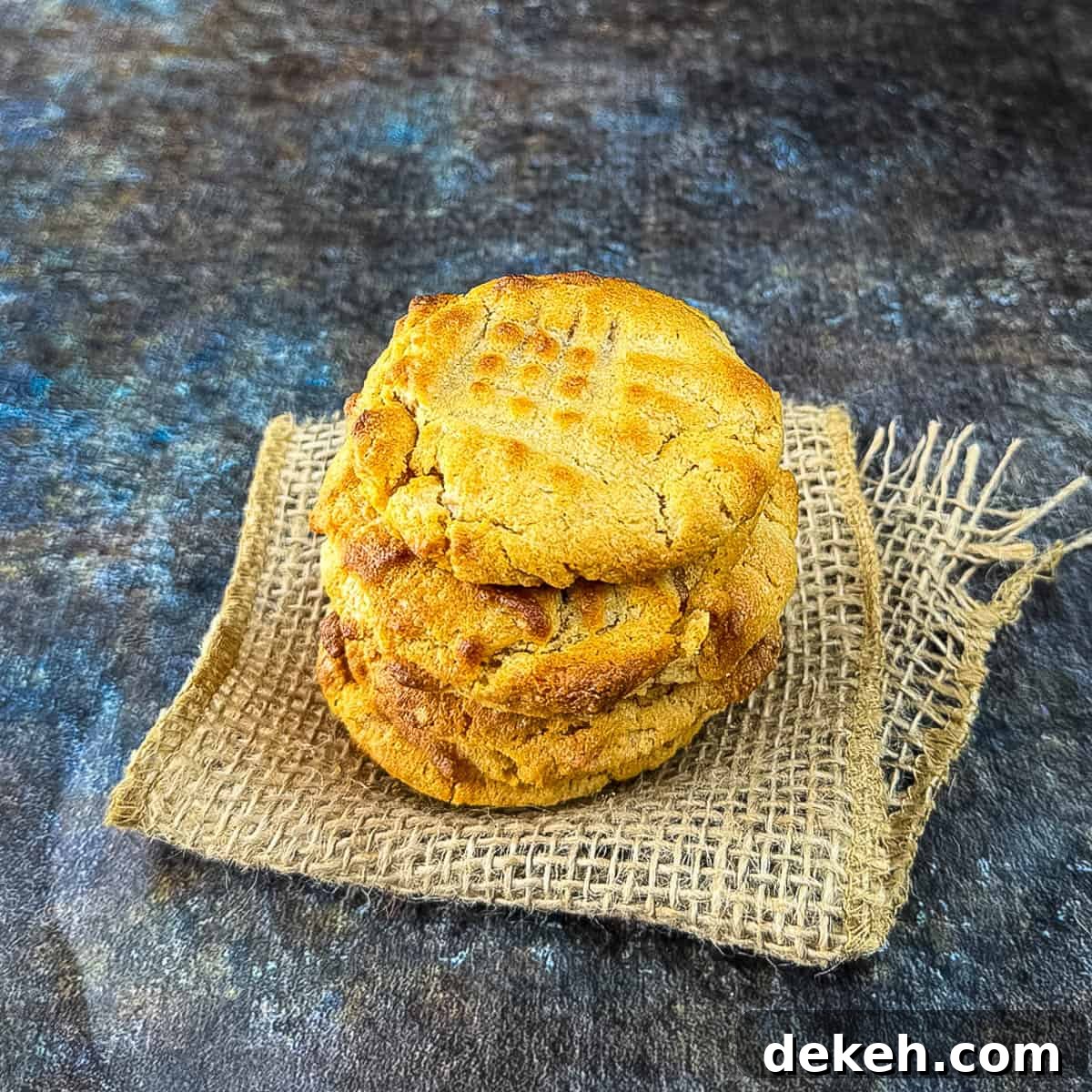 A stack of golden brown peanut butter cookies on a counter.