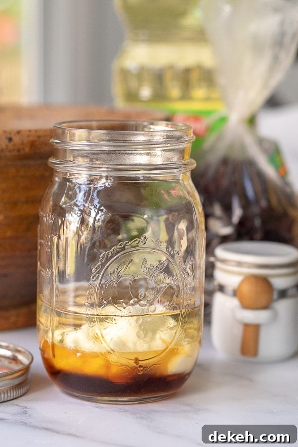 the ingredients for maple dressing in a glass ball jar