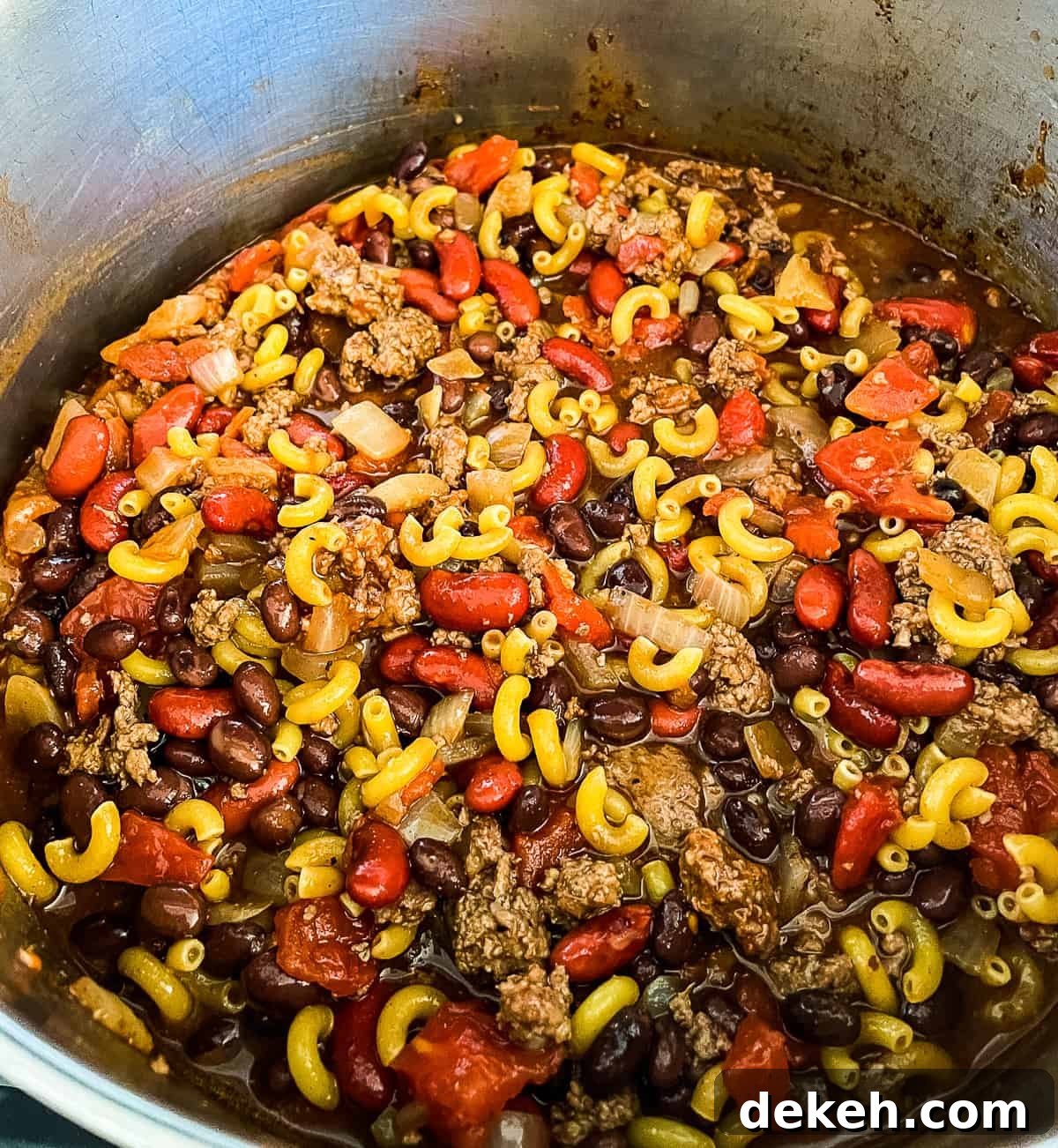 pot of ground beef, diced tomatoes, spices, and macaroni on a stovetop