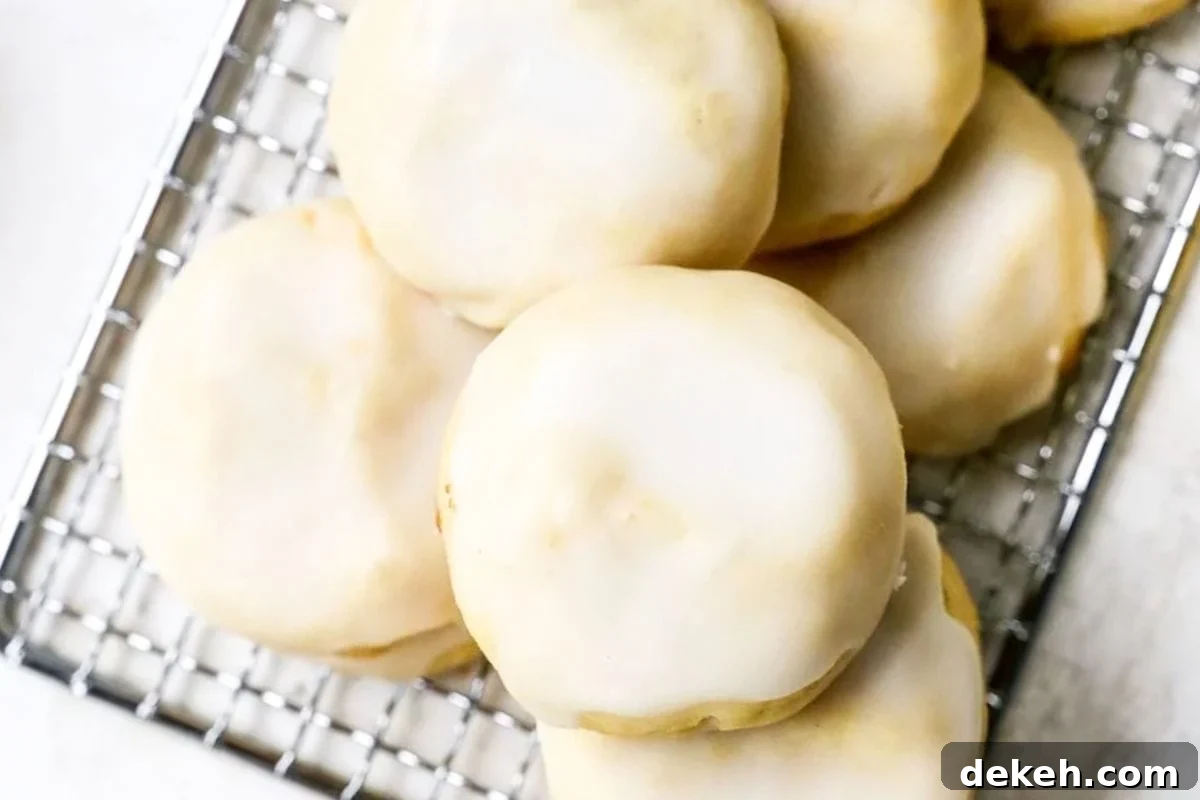 A close-up view of round, iced cookies resting on a wire cooling rack, showcasing their smooth white glaze against a light background.
