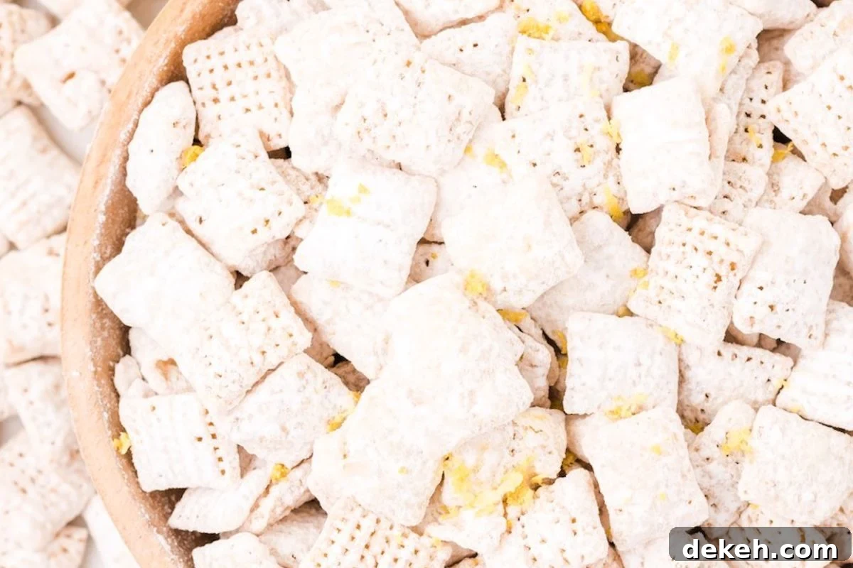 A close-up view of a bowl filled with white, powdered puppy chow snacks, showcasing their crispy texture and sugary coating.