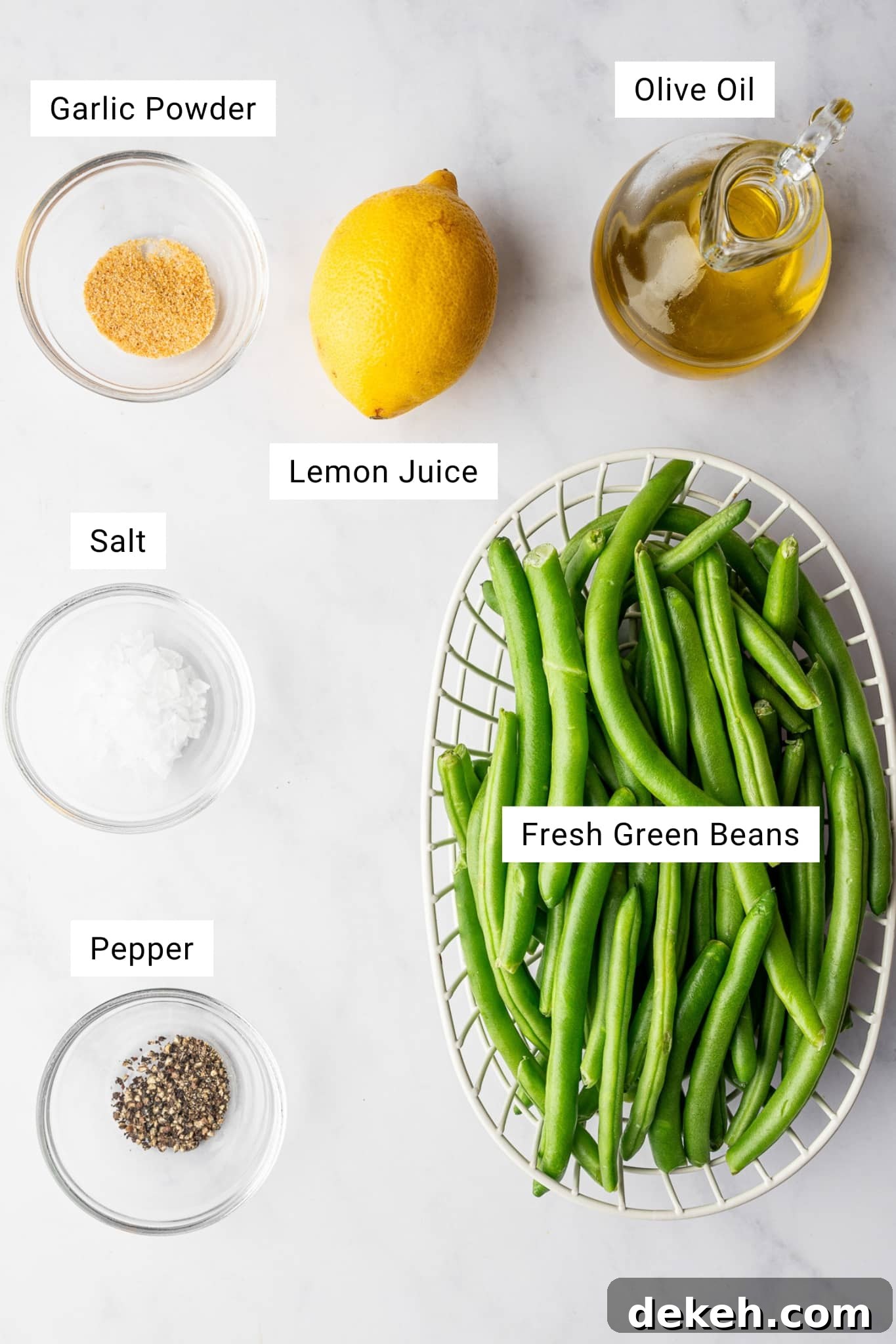 Ingredients for air fryer green beans including fresh green beans, olive oil, garlic powder, lemon, salt, and pepper.