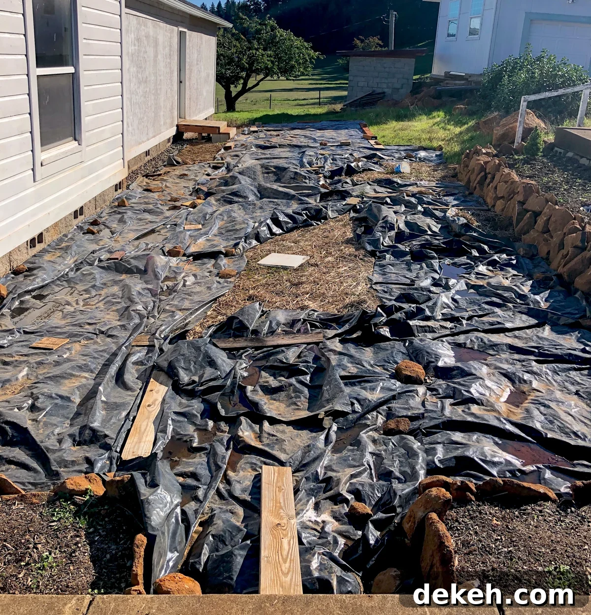 excavated side yard covered in black plastic