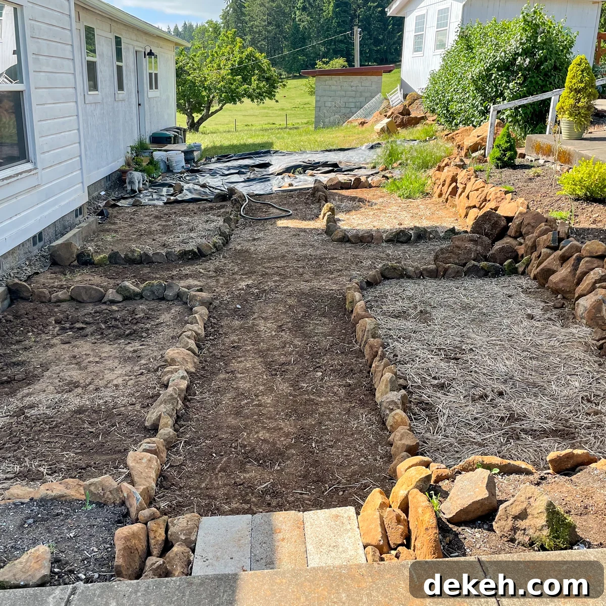 rock wall raised beds and four rock outlined beds for future flowers.