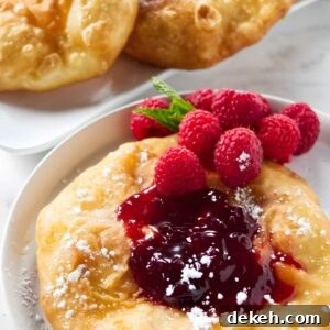 Fried dough with raspberry jam, sugar, fresh raspberries, and mint garnish.