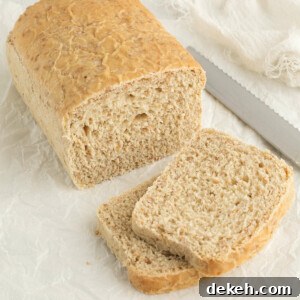 Slices of cracked wheat bread next to a loaf of bread and a knife.