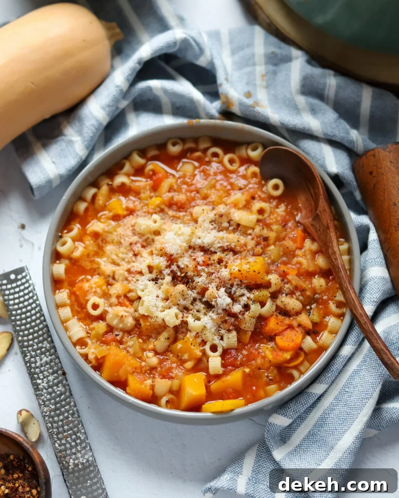 overhead view of a gray bowl filled with vegan pasta fagioli soup with grated brazil nut and red pepper flakes.