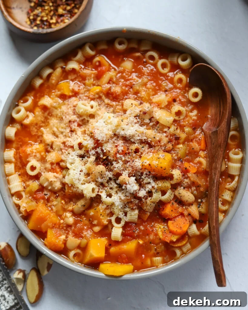 overhead view of a gray bowl of vegetarian pasta e fagioli soup with carrots, butternut squash, ditalini, beans, and more.