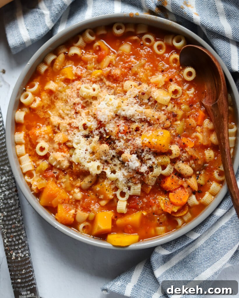close up of a bowl of homemade vegan pasta fagioli soup with root vegetables, squash, and brazil nut instead of non dairy cheese.
