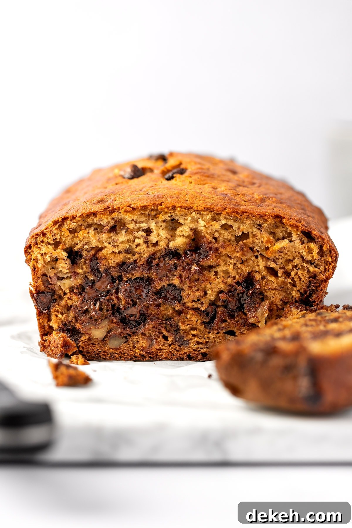 A loaf of ricotta banana bread cut in half, sitting on a white marble serving board.