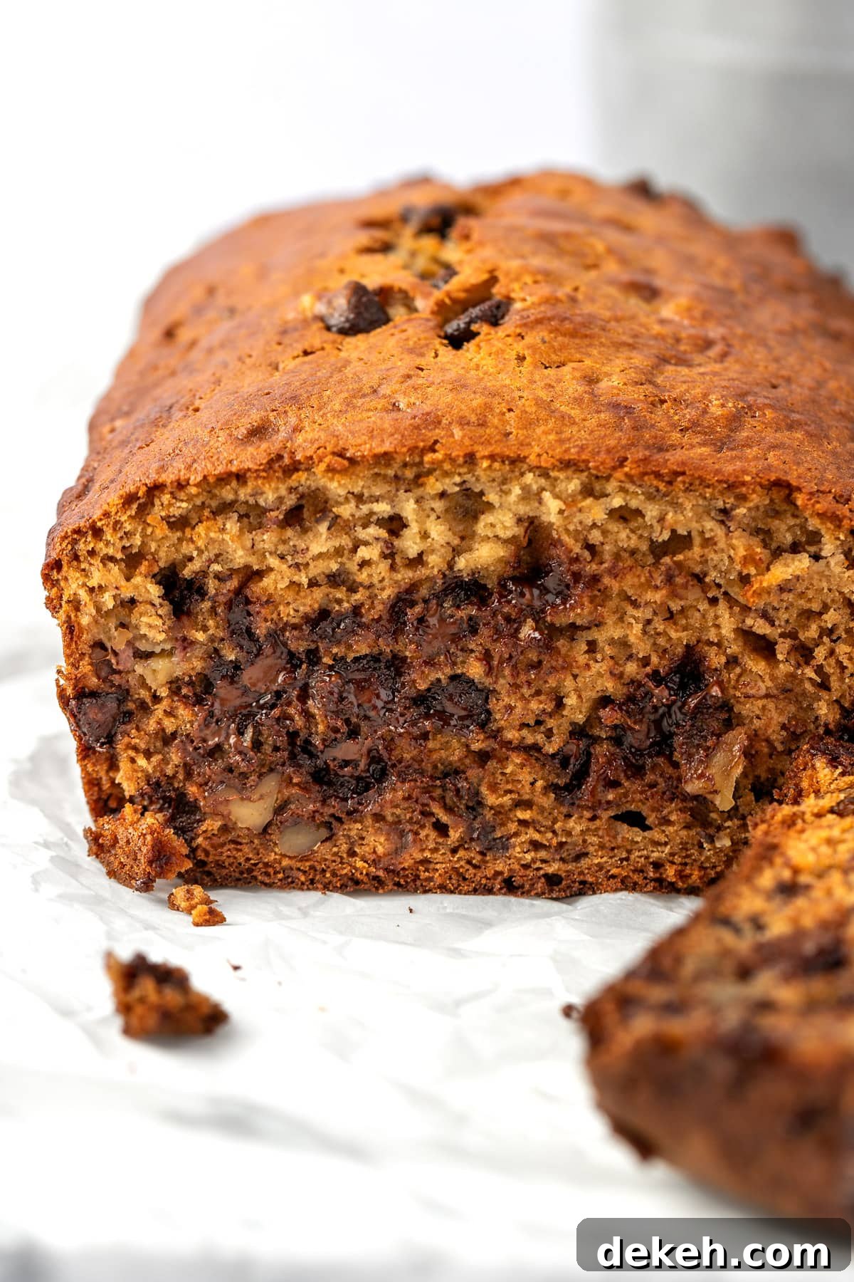 Eye level view of a loaf of ricotta banana bread, cut in half, sitting on parchment paper.