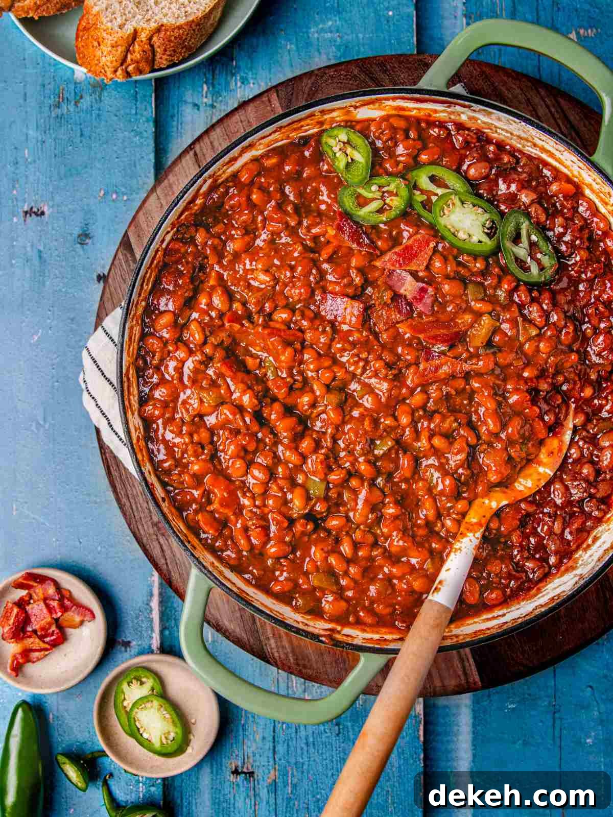 one pot beans casserole in a skillet garnished with jalapenos and bacon.