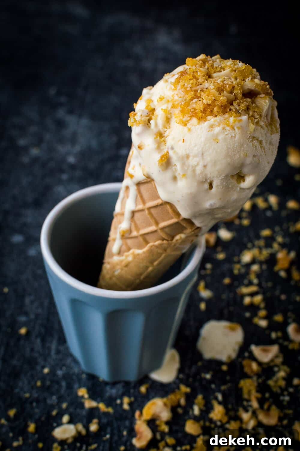Vanilla hazelnut caramel praline ice cream in a cone on a black background.