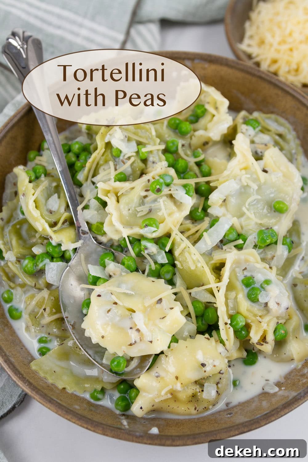 a bowl full of cooked tortellini in a creamy sauce with peas and onions.