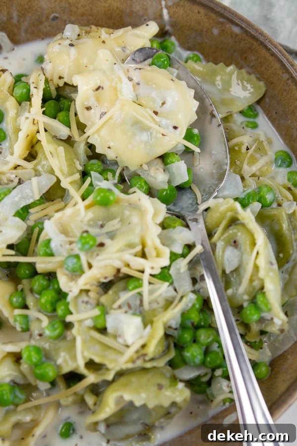 a bowl full of cooked tortellini with a serving spoon.