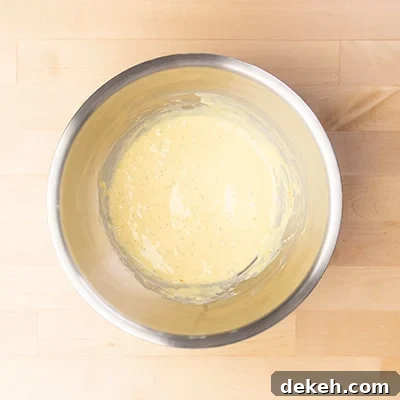 large round metal mixing bowl with light yellow liquid