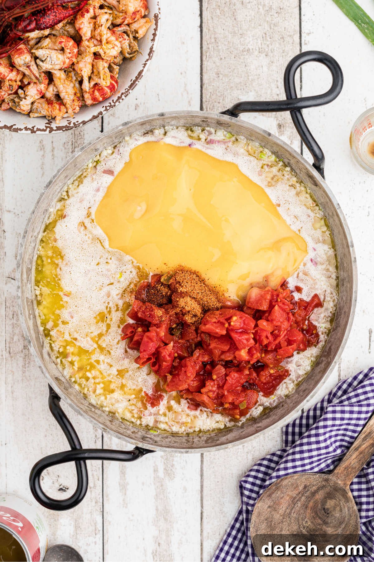 A skillet with some cheese sauce added with some tomatoes.