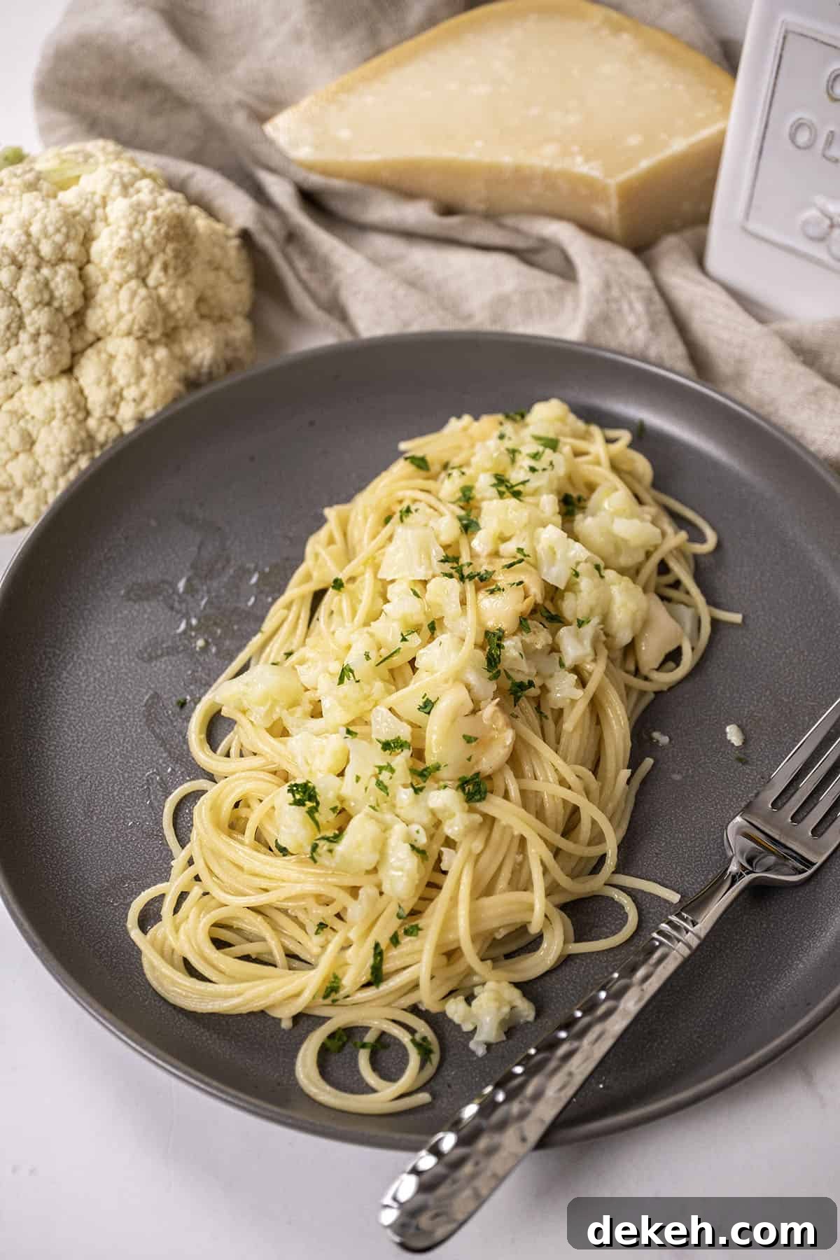 spaghetti with cauliflower plated on a dish garnished with parsley.