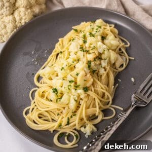 spaghetti with cauliflower plated on a dish garnished with parsley.