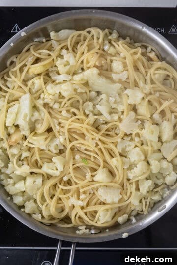 spaghetti added to pan with cauliflower and garlic.