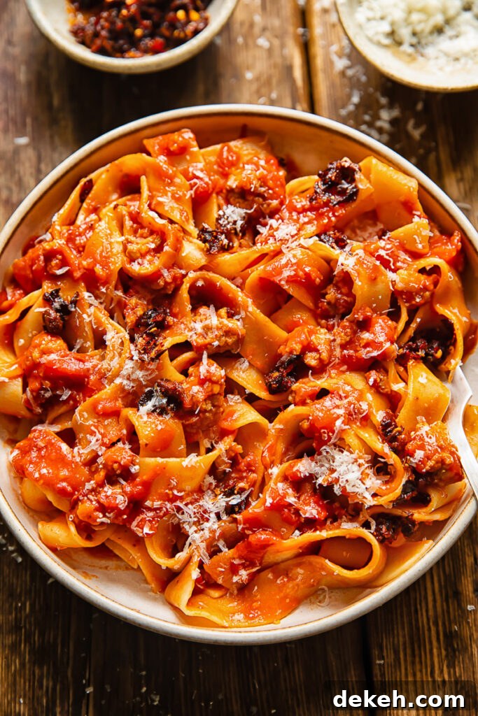 Close up shot of sausage ragu in a bowl with chilli crisp and Parmesan