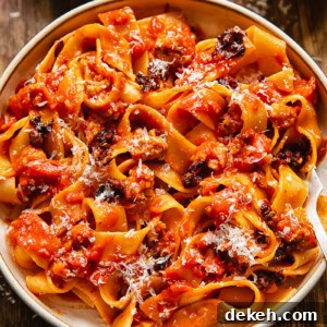 Close up shot of sausage ragu in a bowl with chilli crisp and Parmesan