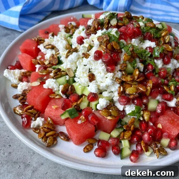 A plate of fresh watermelon, cucumber, and crumbled feta topped with pomegranate seeds, chopped herbs, and caramelized sunflower seeds makes for one of the most refreshing health bites in summer food recipes.
