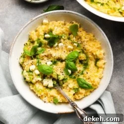 Creamy corn risotto garnished with basil leaves and drizzled with green oil.