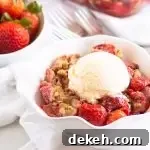 bowl of strawberry crumble topped with ice cream with a bowl of fresh strawberries in the background