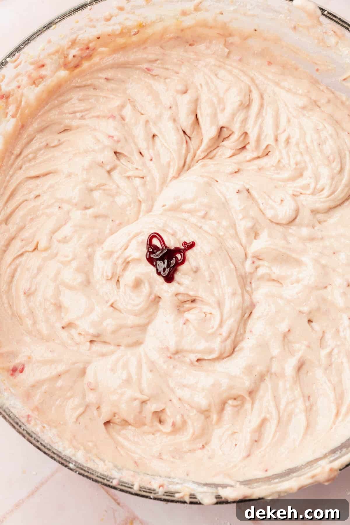 A large mixing bowl with gluten-free strawberry cake batter topped with a little red food coloring before mixing.
