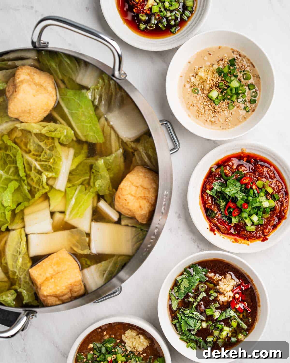 Hot pot with broth and ingredients surrounded by 5 dipping sauces.