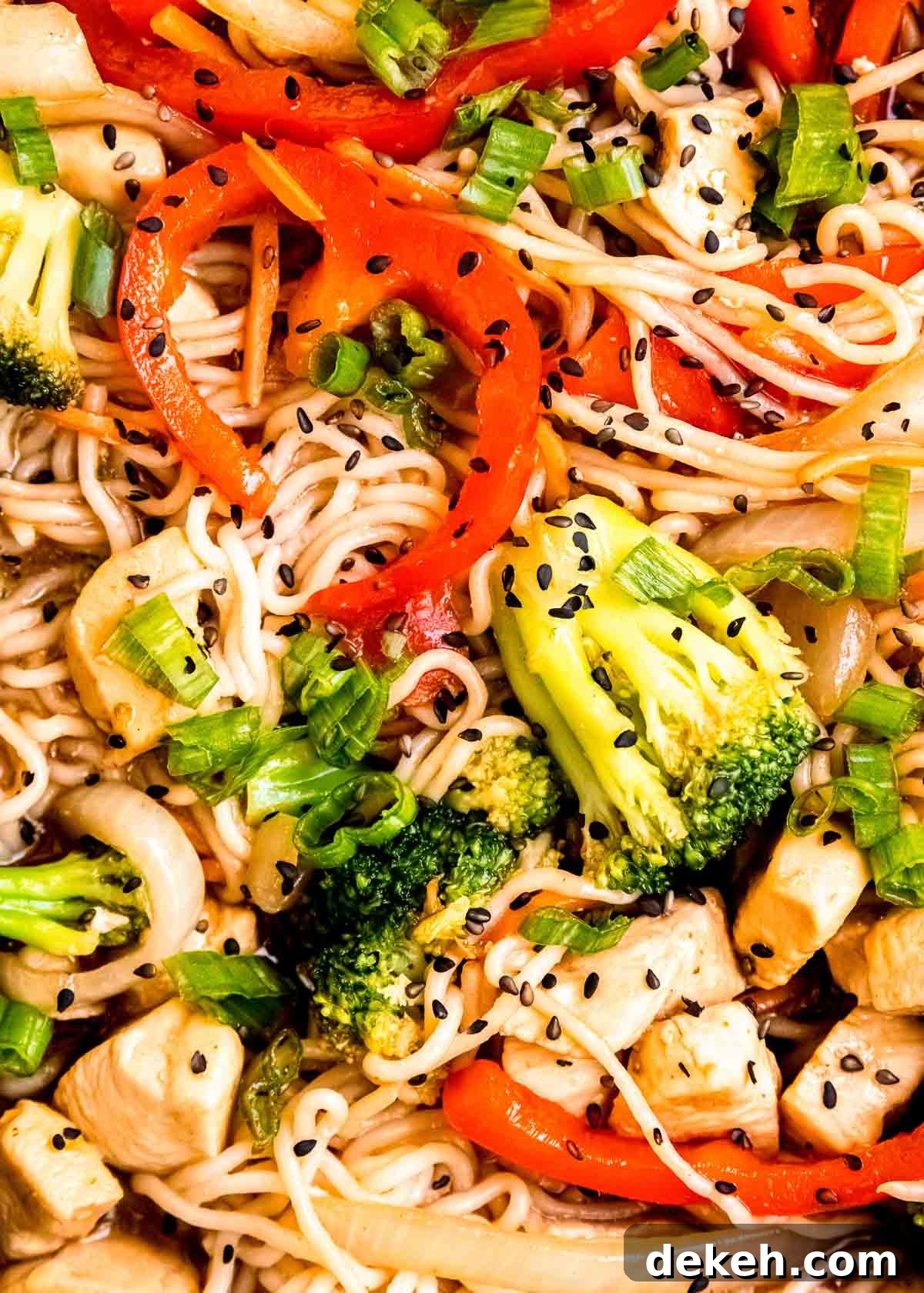 closeup overhead view of shirataki noodle stir fry with chicken, red peppers, broccoli, and onion