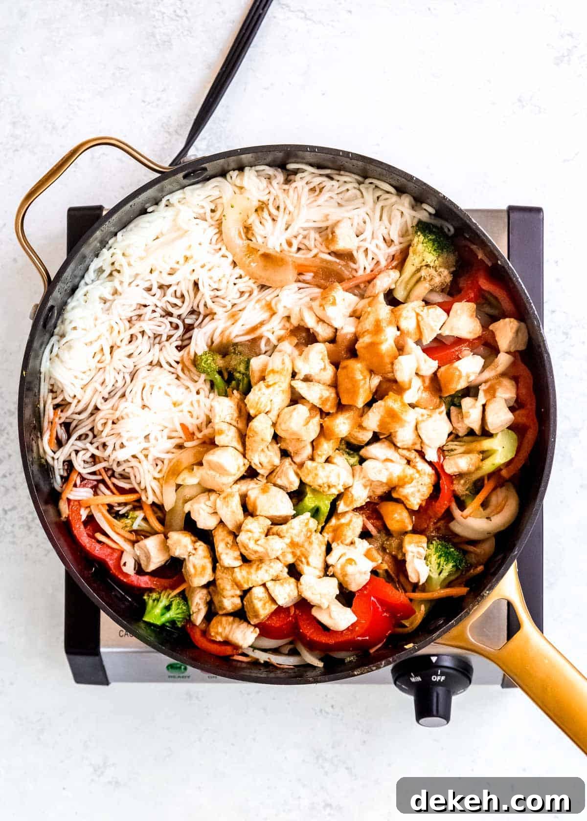 chicken, red peppers, onions, broccoli, carrots, and noodles in a large skillet