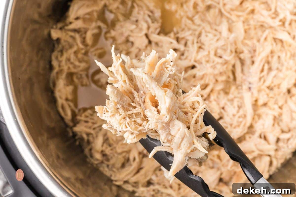 Shredded chicken in an Instant Pot with tong.