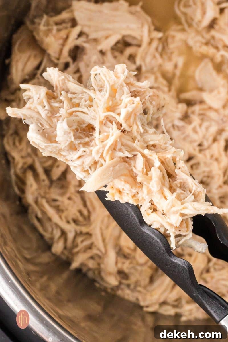 Shredded chicken in an Instant Pot with tong.