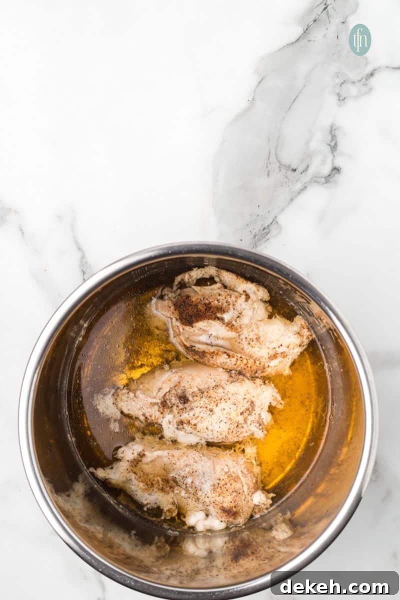 A bowl of cooked chicken with a liquid mixture.
