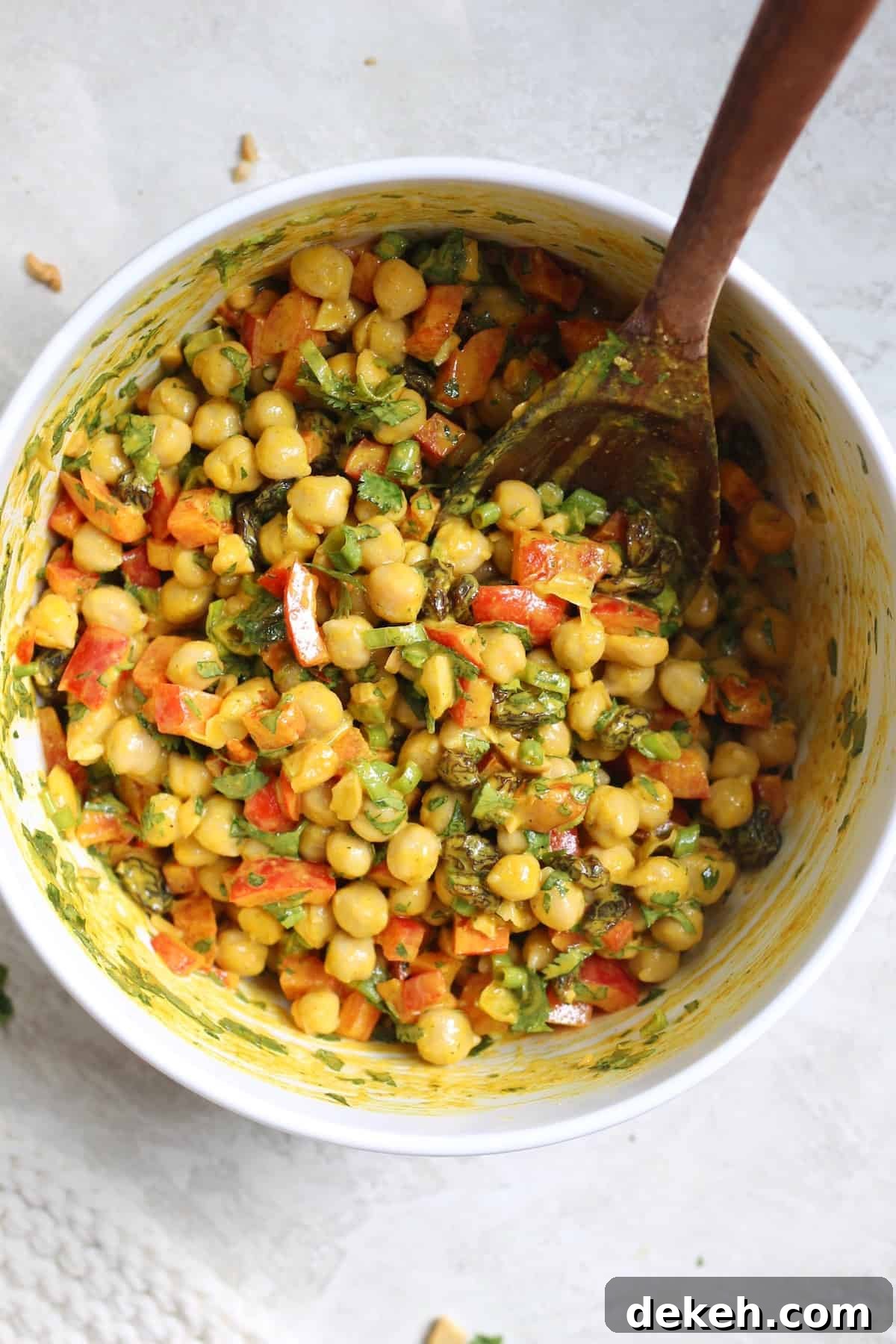 mixing bowl of salad with wooden spoon